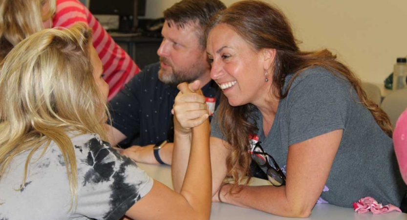 Two people arm wrestle at the family seminar of an outward bound intercept course